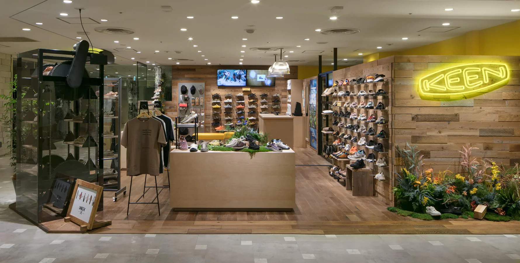 Keen’s retail store layout showing a wall rack of shoes next to a clothing rail of t-shirts.