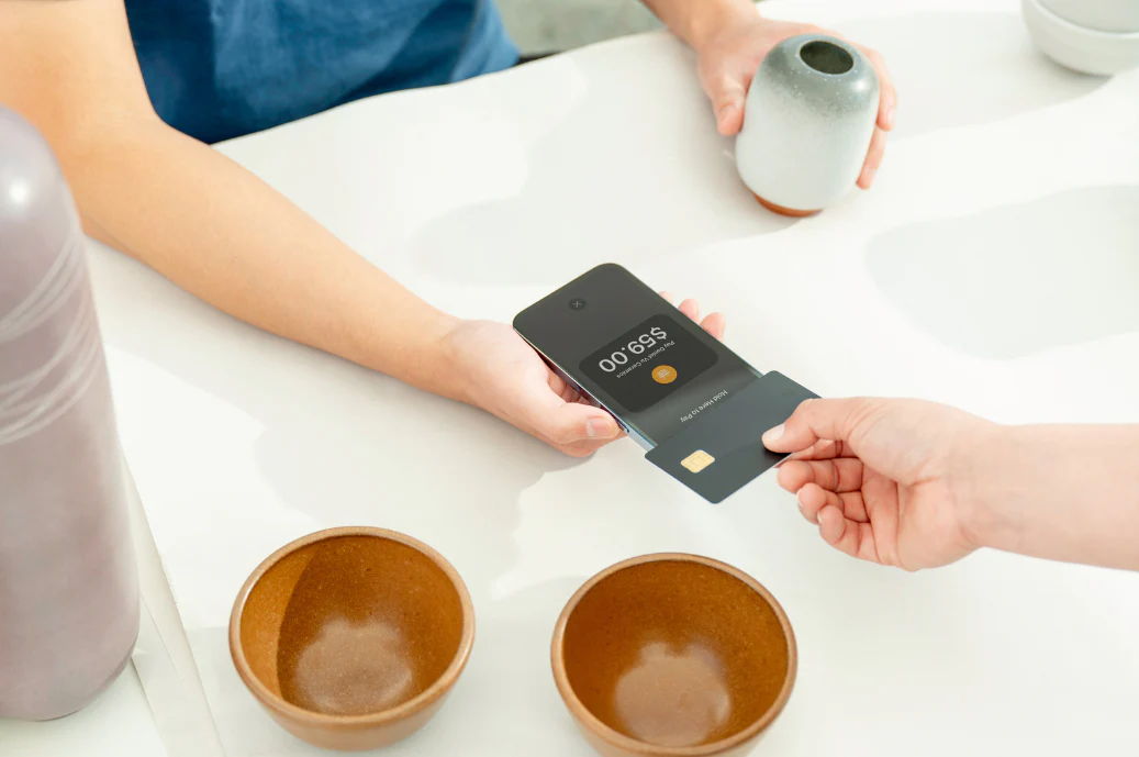 Person tapping their credit card against a smartphone to make a contactless payment.