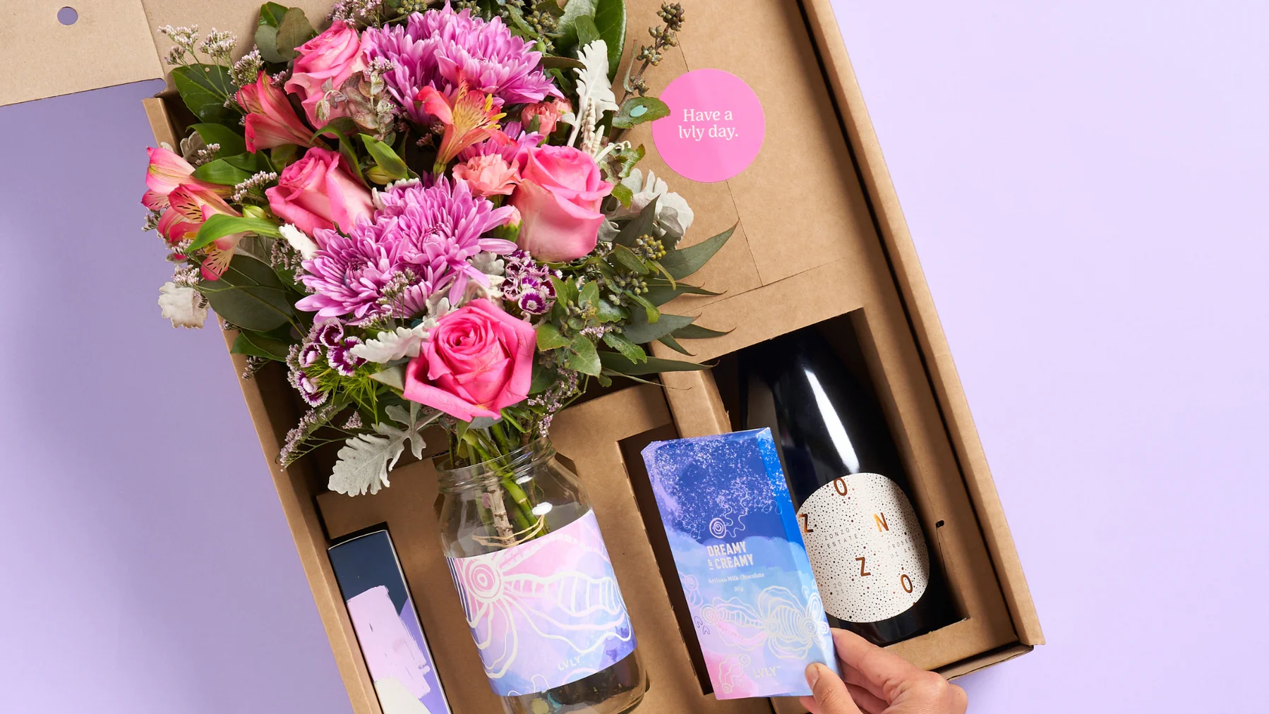 A gift box with a bouquet of flowers, a bottle of wine, and a card.
