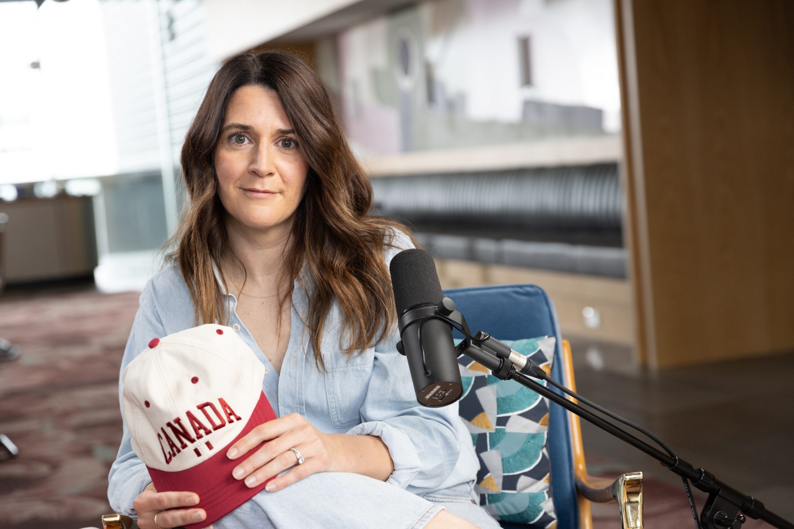 Julie Brown posing with a white Province of Canada hat that says Canada on it in red.