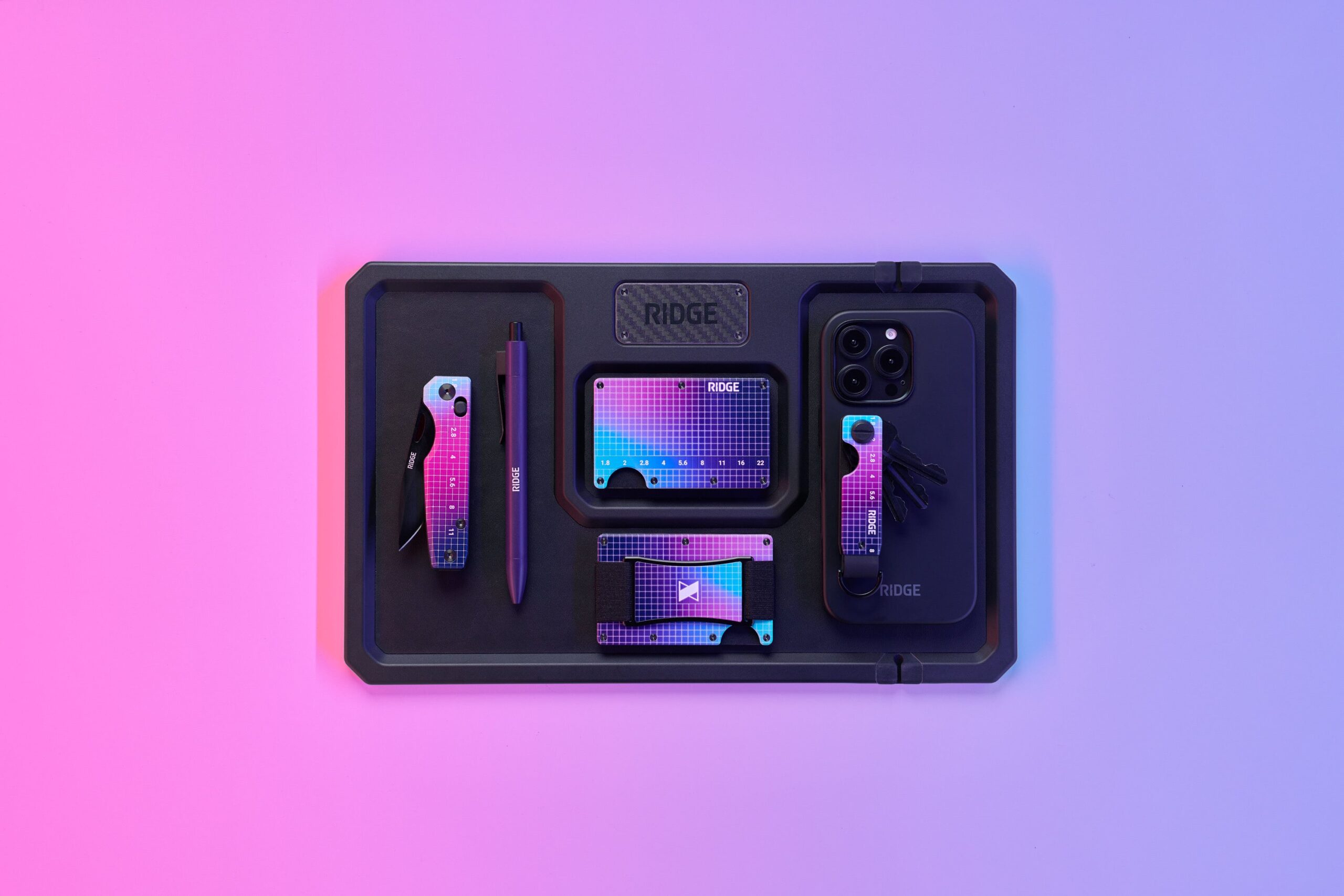 A Ridge wallet against an ombre purple and pink background.