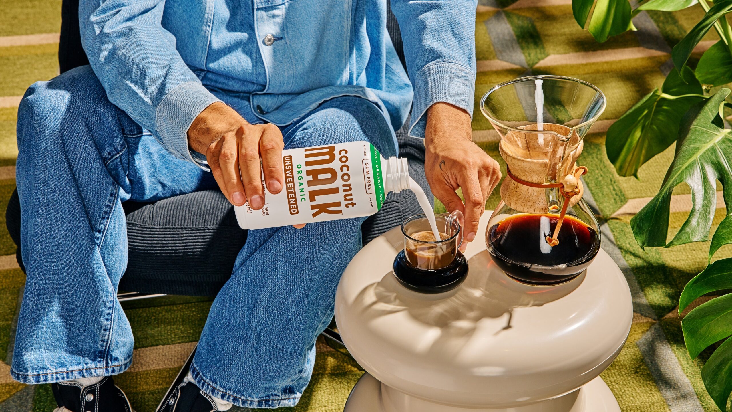A model pours MALK coconut into a cup of hot coffee.