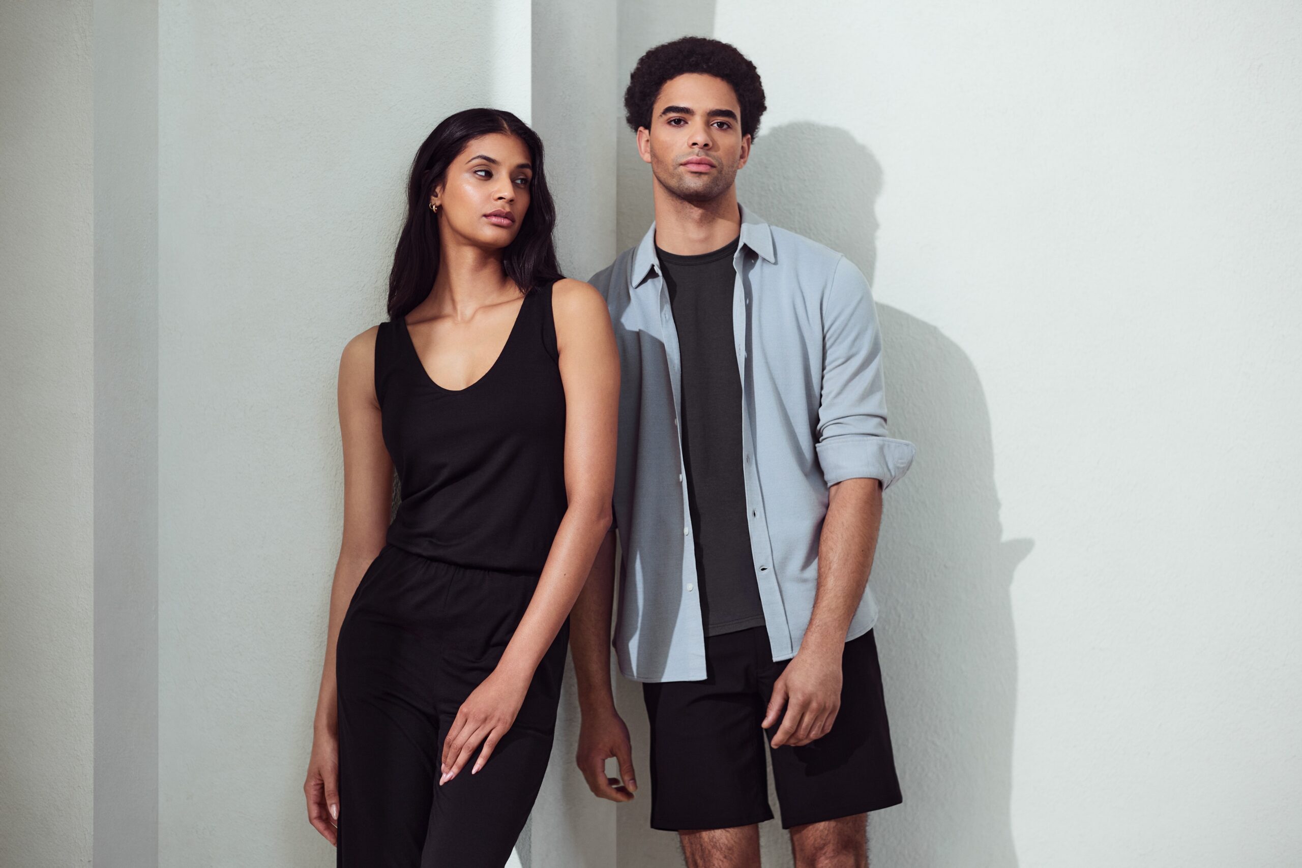 Two models pose side by side wearing Unbound Merino clothing.