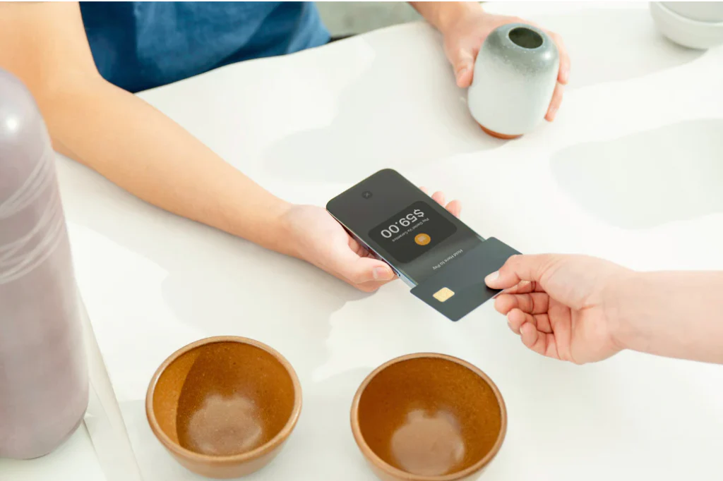 Person tapping their contactless payment card onto a smartphone with Shopify POS.